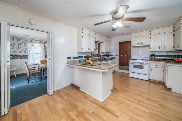 kitchen with white cabinetry, light wood-type flooring, kitchen peninsula, white gas range oven, and backsplash