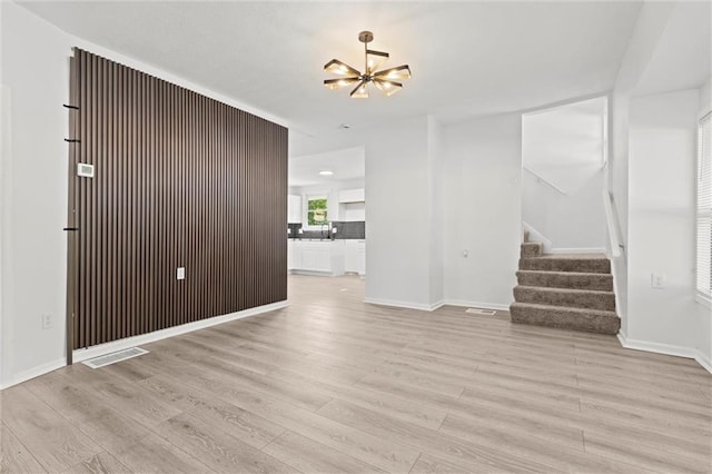 unfurnished living room featuring a chandelier and light hardwood / wood-style floors