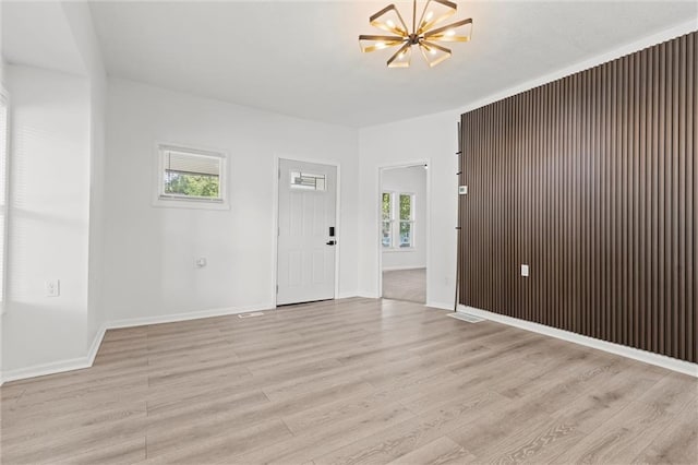 empty room featuring light hardwood / wood-style flooring and a notable chandelier