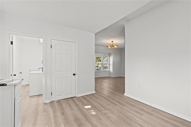 empty room featuring light wood-type flooring and a chandelier