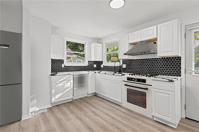 kitchen featuring light wood-type flooring, white cabinets, white appliances, and backsplash