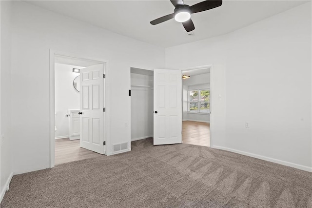 unfurnished bedroom featuring a closet, ceiling fan, light carpet, and connected bathroom