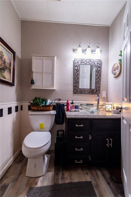 bathroom with wood-type flooring, tile walls, vanity, and toilet