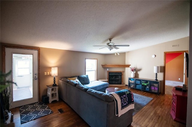 living room with ceiling fan, vaulted ceiling, dark hardwood / wood-style floors, and a textured ceiling