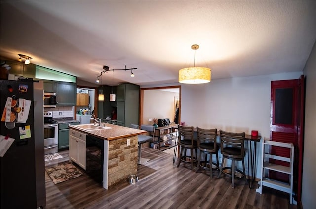 kitchen with dark hardwood / wood-style flooring, a center island with sink, decorative light fixtures, lofted ceiling, and appliances with stainless steel finishes