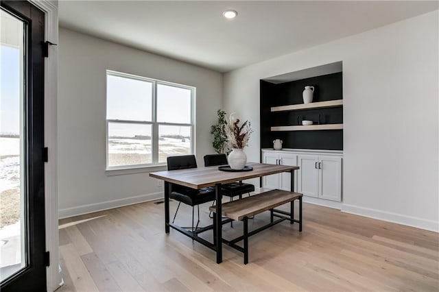 dining space with built in shelves and light hardwood / wood-style floors