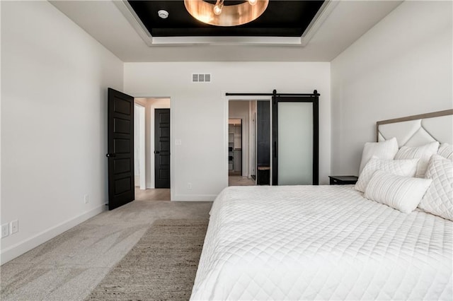 bedroom with a barn door, carpet flooring, and a tray ceiling