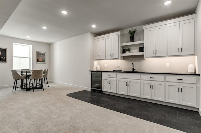 kitchen with tasteful backsplash, sink, white cabinets, beverage cooler, and dark colored carpet