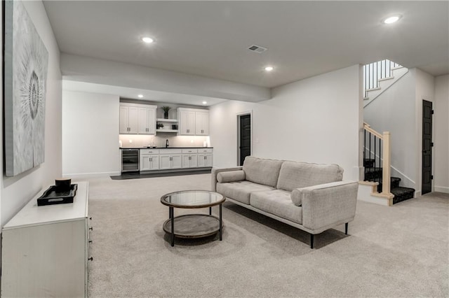 carpeted living room featuring wine cooler and sink