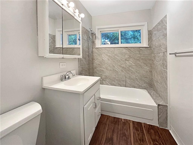 full bath with toilet, wood finished floors, vanity, and shower / tub combination