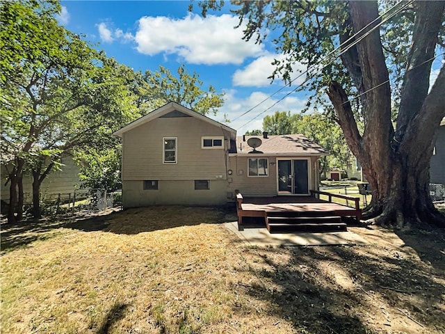 back of property featuring a wooden deck, a lawn, and fence