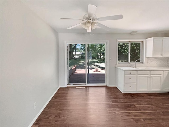 unfurnished dining area featuring a sink, baseboards, dark wood finished floors, and ceiling fan