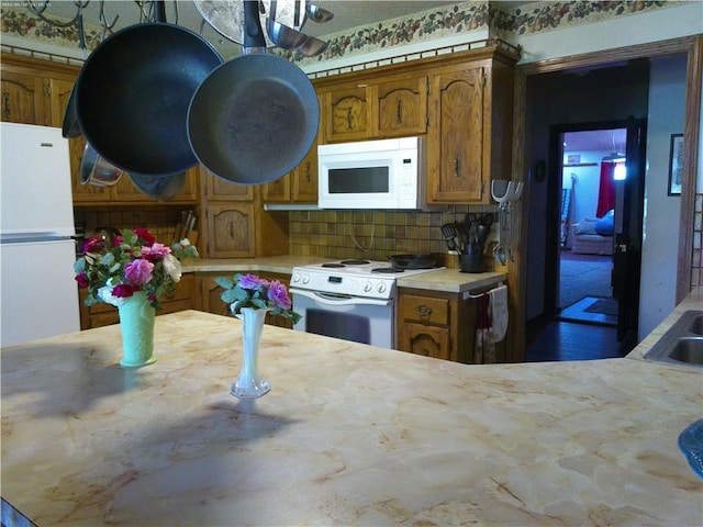 27061 Willow Dr, Paola, KS 66071 - kitchen with white appliances, light countertops, brown cabinets, and tasteful backsplash