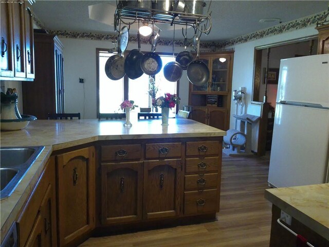 27061 Willow Dr, Paola, KS 66071 - kitchen featuring freestanding refrigerator, light countertops, wood finished floors, and brown cabinets