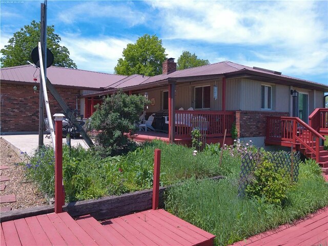 27061 Willow Dr, Paola, KS 66071 - rear view of property with brick siding, a deck, metal roof, and a chimney