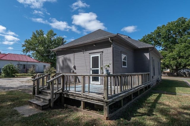 back of house with a deck and a lawn