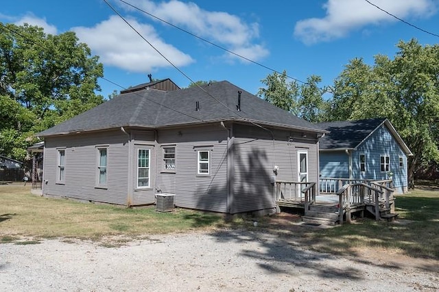 rear view of house featuring a wooden deck and a lawn