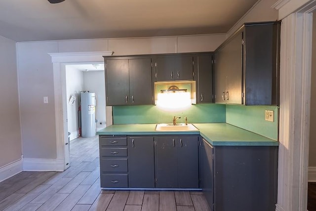 kitchen featuring gray cabinets, light hardwood / wood-style flooring, water heater, and sink