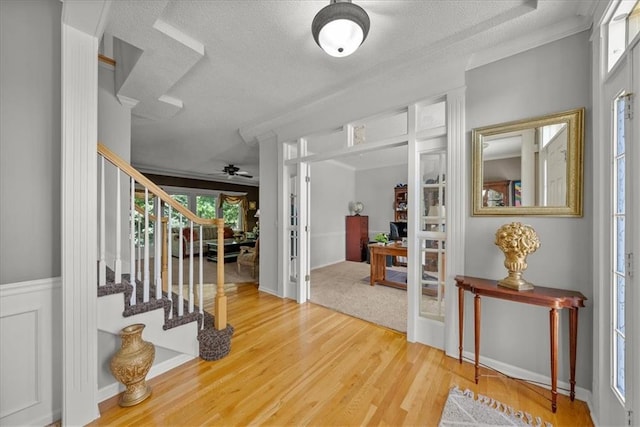 entryway with ceiling fan, a wealth of natural light, hardwood / wood-style flooring, and a textured ceiling