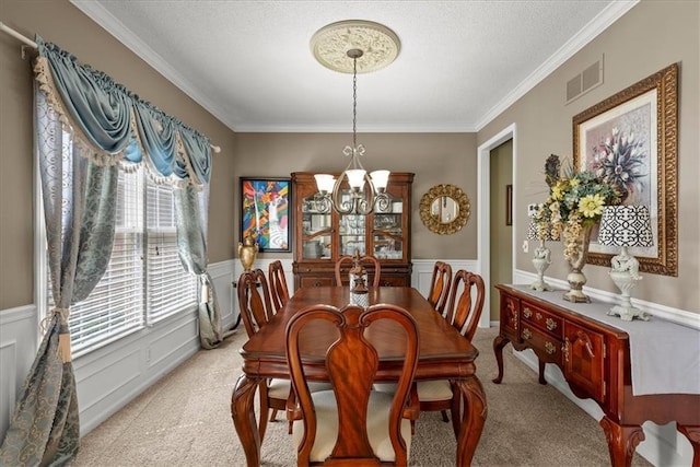 carpeted dining area featuring crown molding, a textured ceiling, and an inviting chandelier