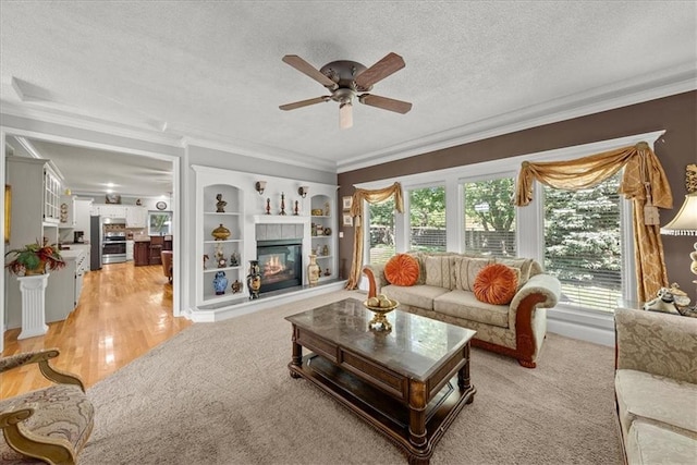 living room featuring a healthy amount of sunlight, ceiling fan, a tile fireplace, and light hardwood / wood-style floors