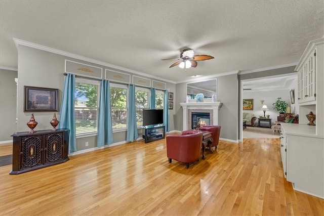 living room with a textured ceiling, ceiling fan, ornamental molding, and light hardwood / wood-style floors