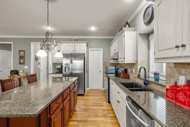 kitchen with pendant lighting, appliances with stainless steel finishes, a center island, sink, and white cabinets