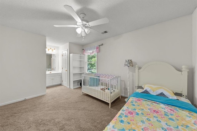 carpeted bedroom featuring ensuite bath, a textured ceiling, and ceiling fan