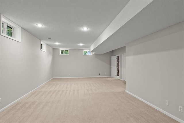 basement featuring a textured ceiling and light colored carpet