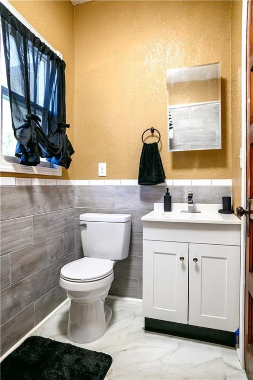 bathroom featuring tile walls, toilet, and vanity