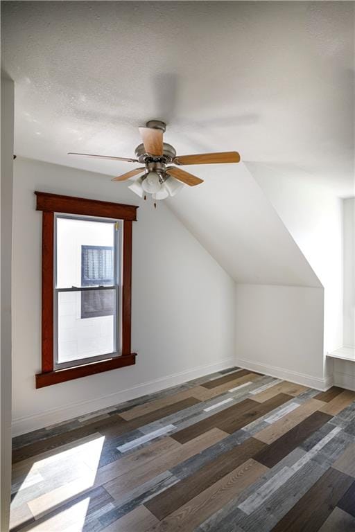 additional living space with vaulted ceiling, dark hardwood / wood-style flooring, ceiling fan, and a textured ceiling