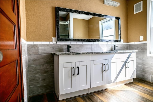 bathroom featuring vanity, backsplash, tile walls, and hardwood / wood-style flooring