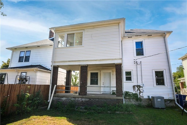 rear view of house with cooling unit, a porch, and a yard