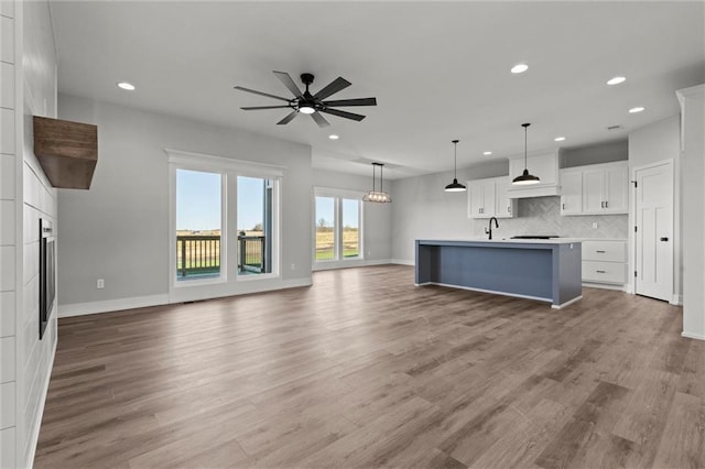 unfurnished living room featuring hardwood / wood-style flooring, ceiling fan, and sink