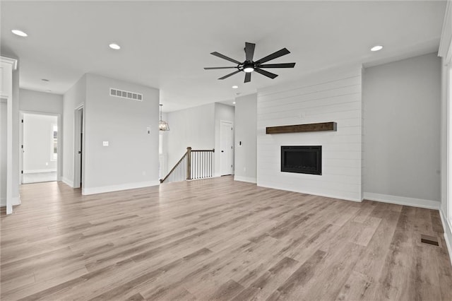 unfurnished living room featuring a fireplace, light hardwood / wood-style floors, and ceiling fan