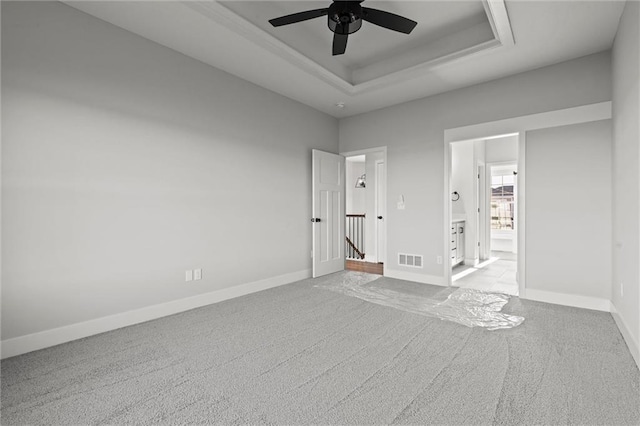 unfurnished bedroom with ceiling fan, a raised ceiling, and light carpet