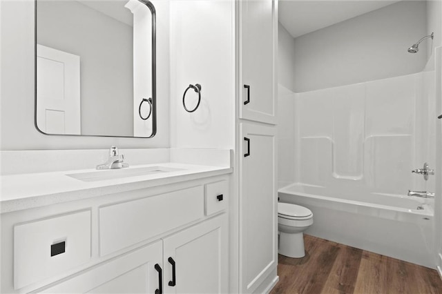 full bathroom featuring washtub / shower combination, hardwood / wood-style floors, vanity, and toilet