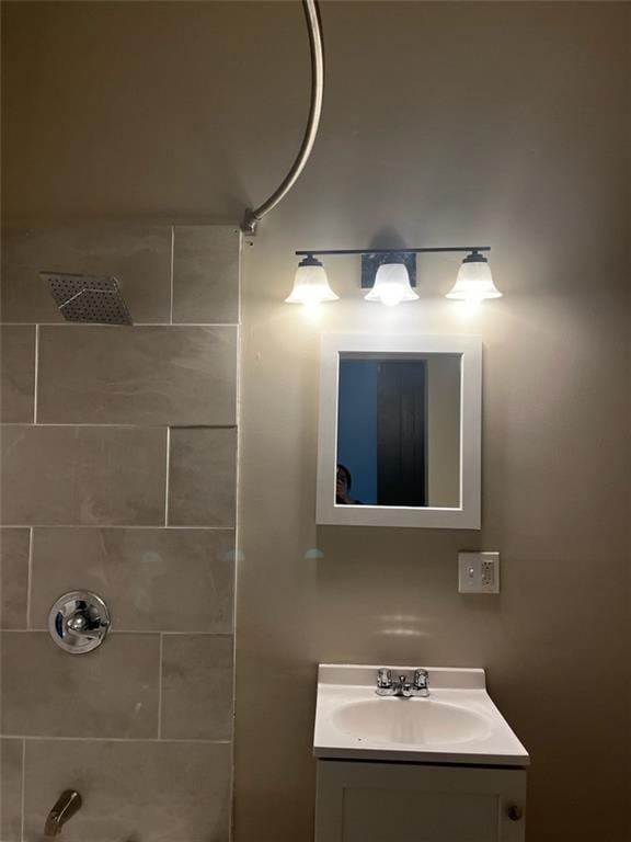 bathroom with tiled shower and vanity