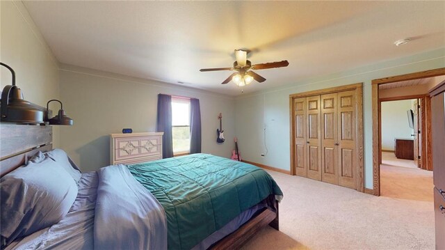 bedroom with ornamental molding, a closet, ceiling fan, and light colored carpet