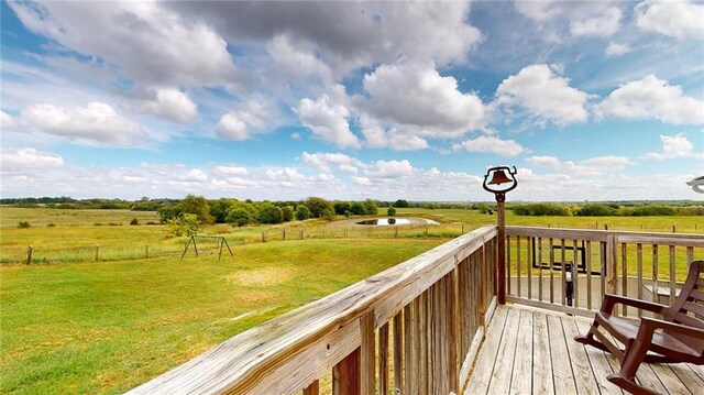 wooden deck with a rural view and a lawn