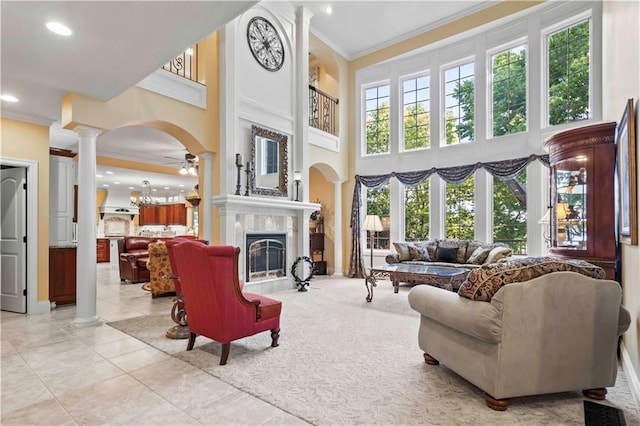 living room featuring crown molding, a healthy amount of sunlight, ceiling fan, and decorative columns