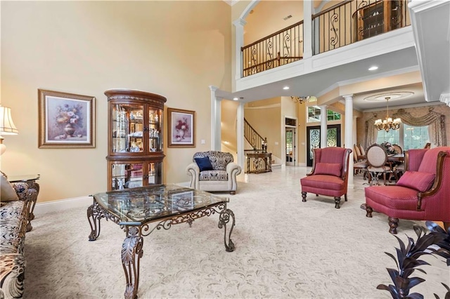 living room featuring ornate columns, ornamental molding, a chandelier, carpet flooring, and a high ceiling