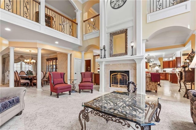 living room with light tile patterned floors, a notable chandelier, decorative columns, a premium fireplace, and a towering ceiling