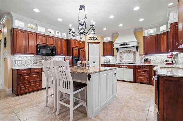 kitchen with a kitchen island, a breakfast bar area, premium range hood, sink, and a chandelier