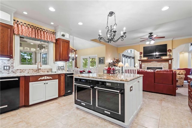 kitchen with ceiling fan with notable chandelier, crown molding, decorative light fixtures, black appliances, and a center island