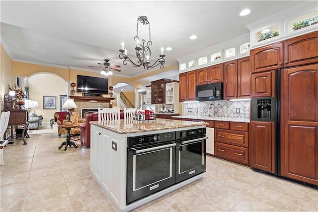 kitchen with ceiling fan with notable chandelier, crown molding, oven, light stone counters, and paneled fridge