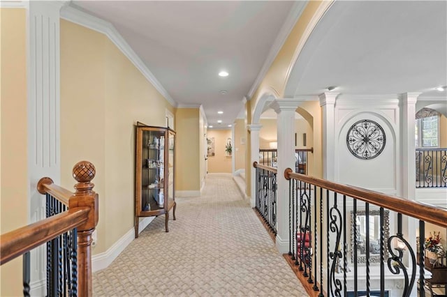 hallway with light carpet, decorative columns, and crown molding