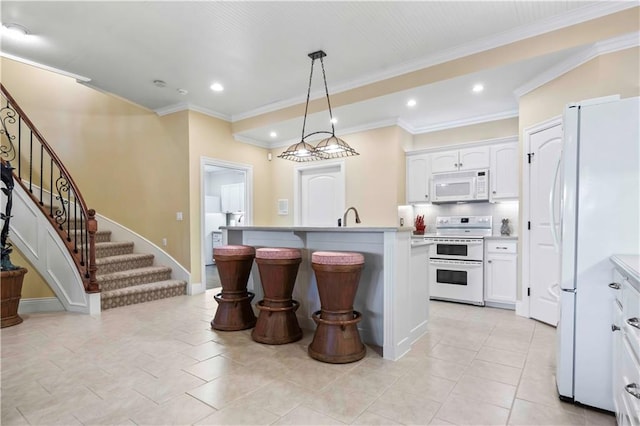 kitchen featuring white appliances, an island with sink, decorative light fixtures, and white cabinets