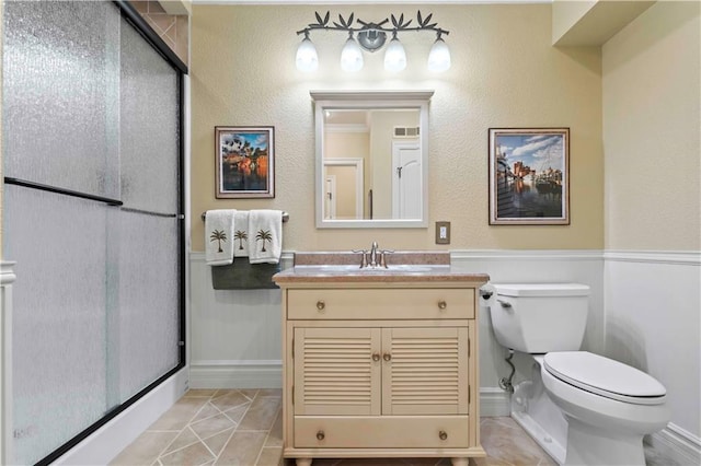 bathroom featuring a shower with door, vanity, toilet, and tile patterned flooring