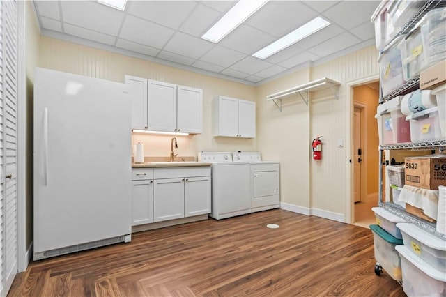 kitchen with white fridge, washer and dryer, sink, white cabinets, and a drop ceiling